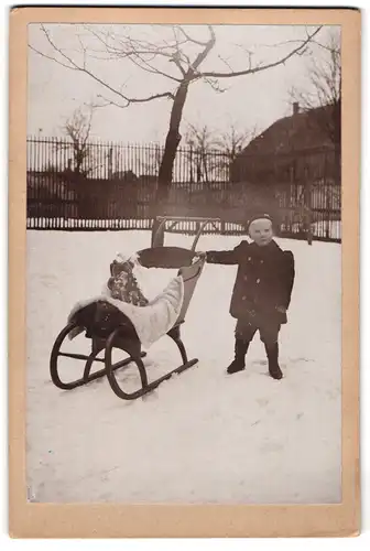 Fotografie unbekannter Fotograf und Ort, junger Knabe Gottfried mit seinem Teddy auf dem Schlitte zu Weihnachten 1909