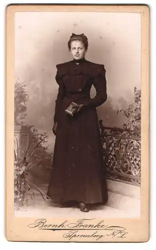Fotografie Bernh. Franke, Spremberg N. L., junge Frau im schwarzen Kommunionskleid mit Lederhandschuhen