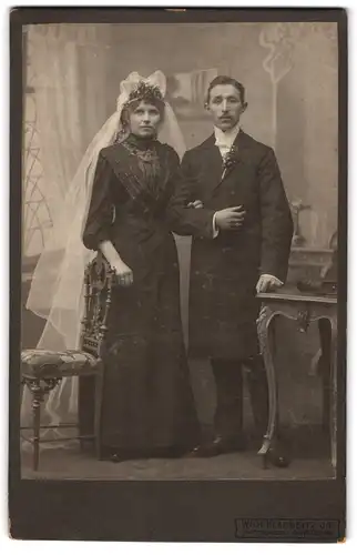 Fotografie Wilh. Klanneitz Jr., Dorsten i. W., Ehepaar im schwarzen Hochzeitskleid und Anzug mit weissem Schleier