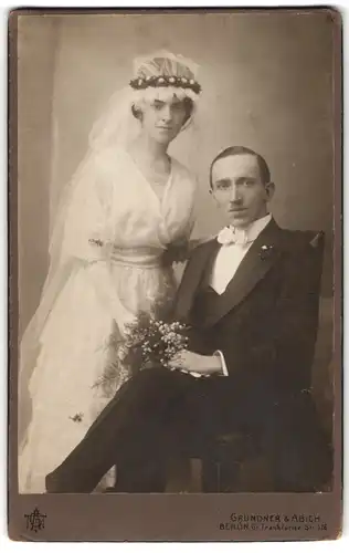 Fotografie Grundner & Abich, Berlin, Ehepaar im Hochzeitskleid mit Schleier und im Anzug mit Brautstrauss