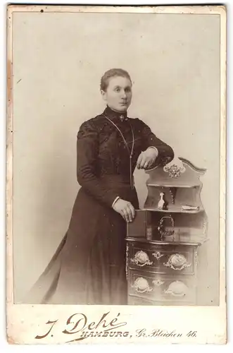 Fotografie J. Dehe, Hamburg, Gr. Bleichen 46, junge Frau lehnend an einer Barock Kommode
