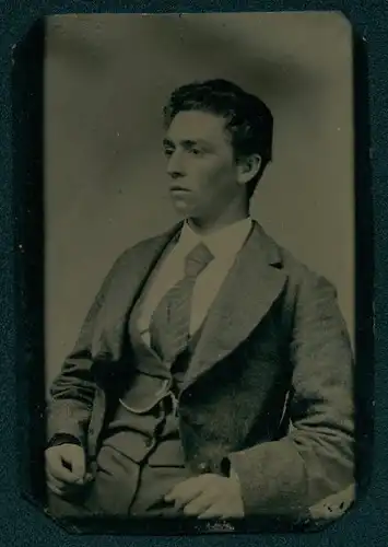 Fotografie Ferrotypie junger Mann im Anzug mit gestreifter Krawatte sitzend im Atelier