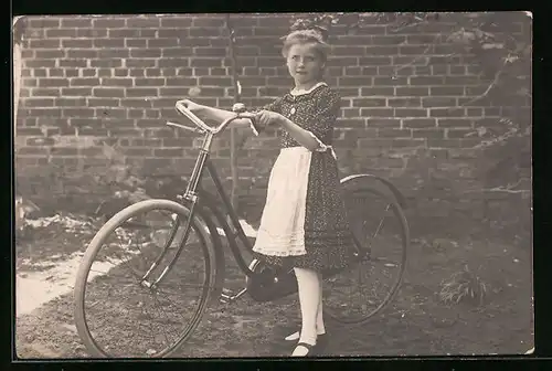 Foto-AK Mädchen im Kleid mit Schürze und Fahrrad