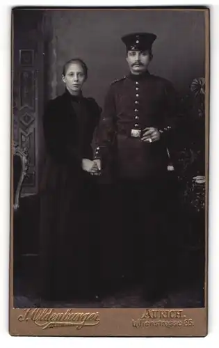 Fotografie J. Oldenburger, Aurich, Uhlandstr. 85, Soldat in Uniform mit Schirmmütze und Frau