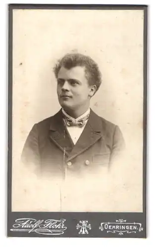 Fotografie Adolf Flohr, Oehringen, Freundlicher junger Mann mit Locken und Fliege