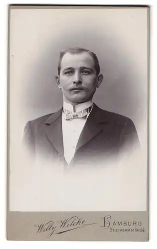 Fotografie Willy Wilcke, Hamburg, Steindamm 54 /56, elegant gekleideter junger Mann mit Schnurrbart und Fliege