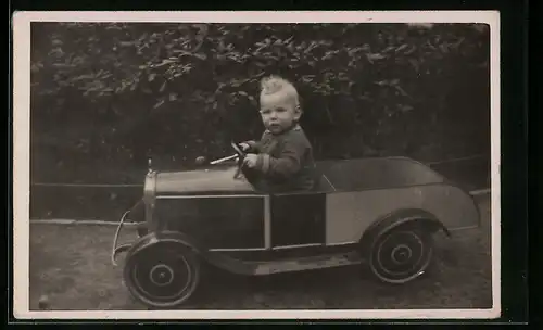 Foto-AK Kleiner Junge im Garten in einem Auto, Spielzeug