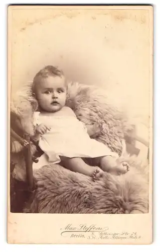 Fotografie Max Steffens, Berlin, Lothringer-Str. 54, Kleinkind im Hemd sitzt auf einem Fell