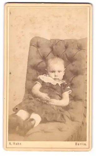 Fotografie A. Hahn, Berlin-C., Landsberger-Str. 82, Kind im Kleid sitzt auf einem Sessel