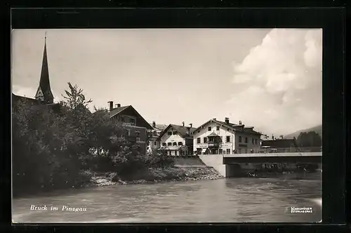 AK Bruck im Pinzgau, Uferpartie mit Schuhgeschäft und Kirchturmspitze