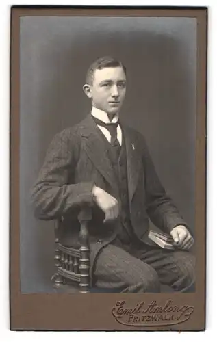 Fotografie Emil Amlong, Pritzwalk, eleganter Mann im schwarzen Anzug sitzend mit Buch