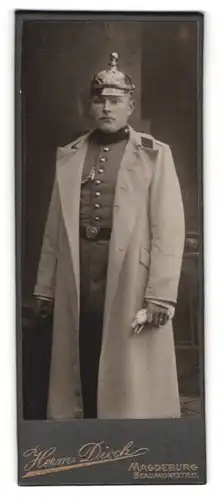 Fotografie Herm. Dieck, Magdeburg, Soldat in Uniform mit Artillerie Pickelhaube und Uniformmantel