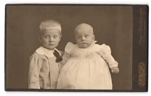 Fotografie Heinr. Stadelmann, Wernigerode a. H., Ringstr. 9, Portrait frecher blonder Bube mit Baby im Taufkleidchen
