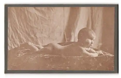 Fotografie unbekannter Fotograf und Ort, Portrait nacktes Baby liegt auf einer bestickten Decke