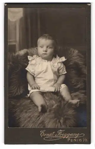 Fotografie Ernst Freygang, Penig i. S., niedliches Kleinkind in weissem Hemdchen auf einem Fell sitzend