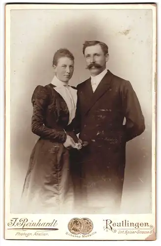 Fotografie F. Reinhardt, Reutlingen, Unt. Kaiser-Str. 9, gutbürgerliches Ehepaar im Frack und schwarzem Kleid mit Rose