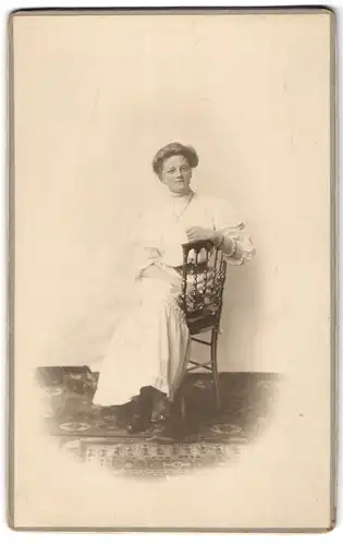 Fotografie unbekannter Fotograf und Ort, Dame auf einem Stuhl sitzend im weissen Sommerkleid mit breitem Taillengürtel