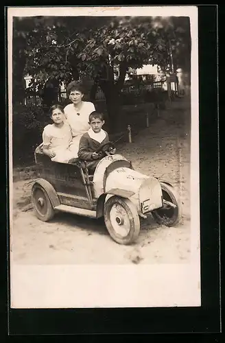 Foto-AK Mutter und zwei Kinder in einem Spielzeug-Auto im Garten