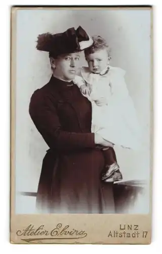 Fotografie Atelier Elvira, Linz, Altstadt 17, Portrait stolze Mutter mit Hut im Kleid hält süsses Tochter auf dem Arm