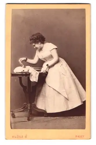 Fotografie Klösz G., Pesten, Portrait Josefine Gallmeyer im Hausfrauenkleid beim Teller abtrocknen, Schauspielerin