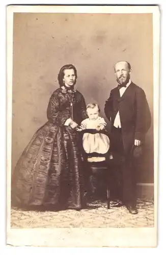 Fotografie unbekannter Fotograf und Ort, Mutter und Vater posieren mit ihrem Kleinkind im Atelier
