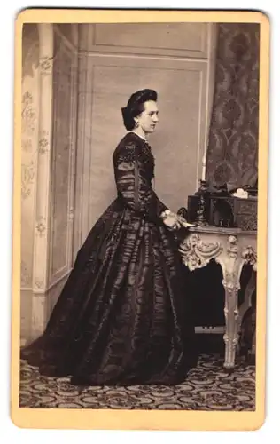 Fotografie Otto v. Zabuesnig, Kempten, junge Dame im dunklen Kleid stehend am Sekretär