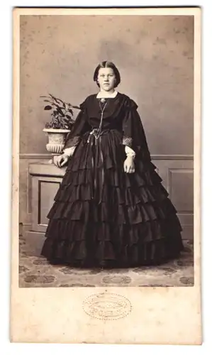 Fotografie B. Täschler, St. Gallen, junge Frau im schwarzen gerafften Kleid mit Brosche