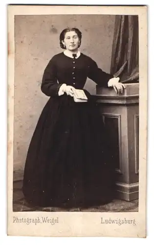 Fotografie Weigel, Ludwigsburg, junge Dame im schwarzen Kleid mit Buch in der Hand