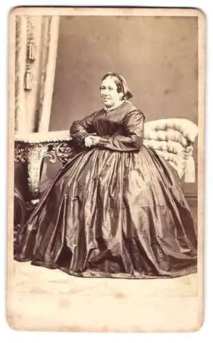 Fotografie Franz Boden, Glatz, ältere Dame im seidenen Reifrockkleid sitzend im Atelier