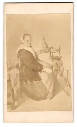Fotografie J. B. Kilian, Ort unbekannt, Gemälde: ältere Dame als Spinnerin am Spinnrad