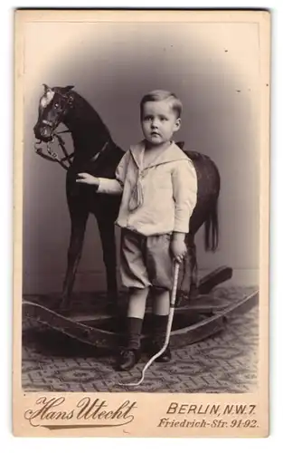 Fotografie Hans Utecht, Berlin, junger Knabe mit grossem Schaukelpferd und Peitsche im Atelier