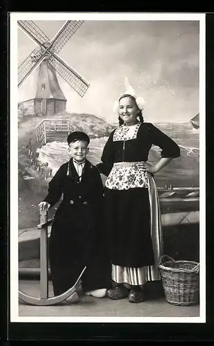 AK Junge Dame und Bube in niederländischen Trachten, Blick zur Windmühle