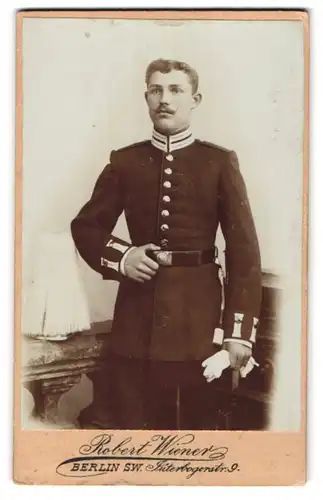 Fotografie Robert Wiener, Berlin, Soldat in Gardeuniform mit Picklehaube Rosshaarbusch auf dem Tisch