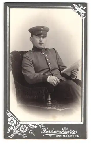 Fotografie Gustav Bopp, Weingarten, Einjährig-Freiwilliger Soldat in Uniform Zeitung lesend im Atelier