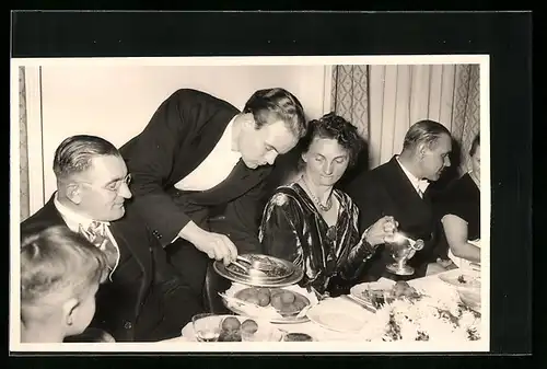 AK Kellner serviert einer feinen Tischgesellschaft Essen