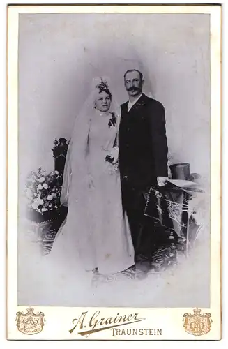 Fotografie A. Grainer, Traunstein, Ehepaar im Hochzeitskleid und Anzug mit Schleier und Zylinder