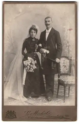 Fotografie G. Michel, Strassburg, franzöisches Brautpaar im schwarzen Kleid und Anzug mit Brautstrauss und Zylinder