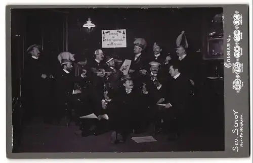 Fotografie Sev. Schoy, Colmar i. Els., Herren der Simfonie Gesellschaft beim Umtrunk mit lustigen Hüten, Fasching