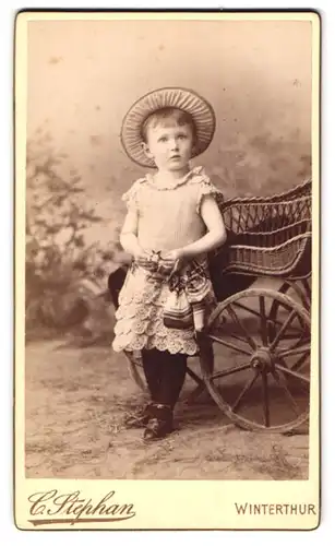 Fotografie C. Stephan, Winterthur, niedliches Mädchen im Sommerkleid stehend am Kinderwagen