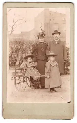 Fotografie unbekannter Fotograf und Ort, Familie mit zwei Mädchen auf einem Karren im Hof