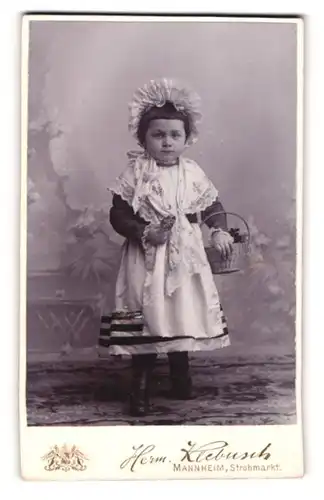 Fotografie Herm. Klebusch, Mannheim, niedliches kleines Mädchen im Kleidchen mit Haube und Blumenkorb