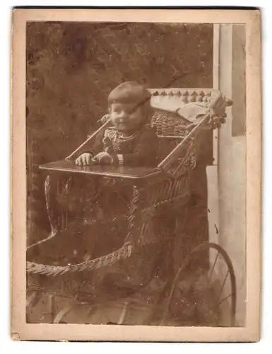 Fotografie unbekannter Fotograf und Ort, niedliches Kleinkind sitzt im Kinderwagen