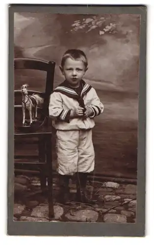 Fotografie Hugo Kopp, Karlsruhe, junger Knabe im Matrosenanzug mit Spielzeug Pferd