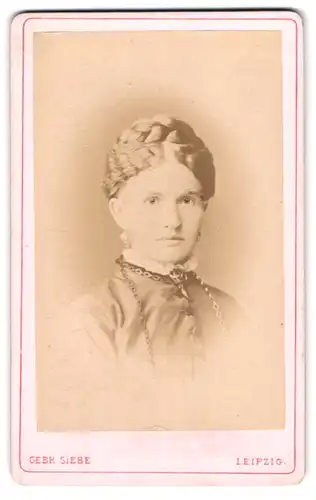 Fotografie Gebr. Siebe, Leipzig, junge Frau im Kleid mit Brosche und geflochtenen hochgesteckten Haaren
