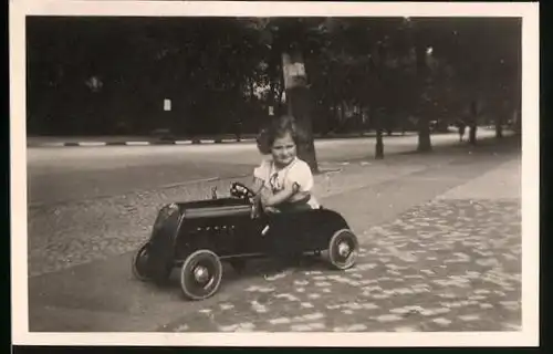 Fotografie Tretauto / Seifenkiste, kleines Mädchen in Spielzeug-Auto sitzend