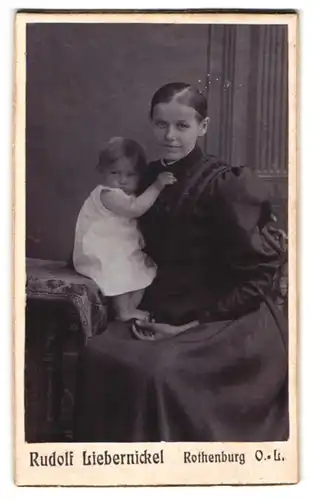 Fotografie Rudolf Liebernickel, Rothenburg / Oberlausitz, Mutter im schwarzen Kleid mit ihren Kind auf dem Schoss