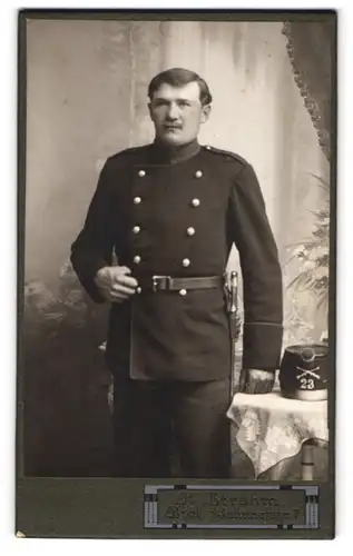 Fotografie P. Strahm, Biel, Soldat der Schweiz in Uniform Rgt. 23 mit Bajonett und Tschako auf dem Tisch