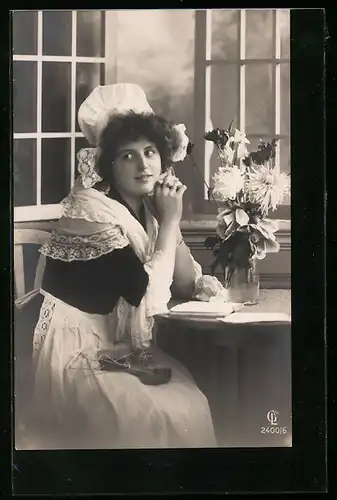 Foto-AK GL Co: Junge Frau in Tracht sitzt wartend am Fenster