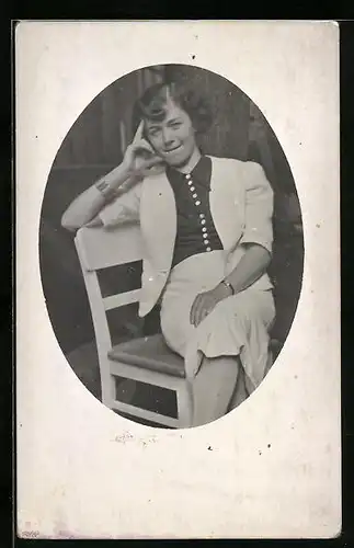 Foto-AK Legere Dame mit abstützender Hand auf einem Stuhl sitzend
