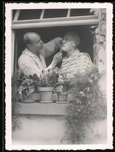 Fotografie Barbier rasiert einen Kunden am offenen Fenster